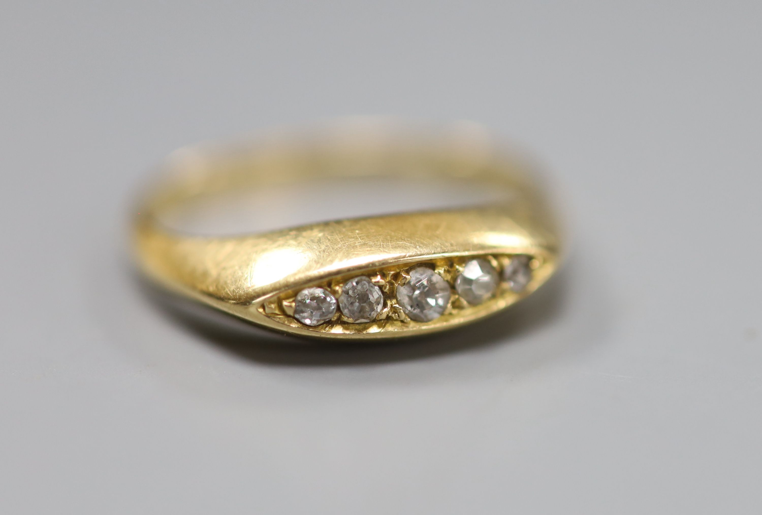 An 18ct gold and five stone diamond set half hoop ring, size J, gross 3 grams.